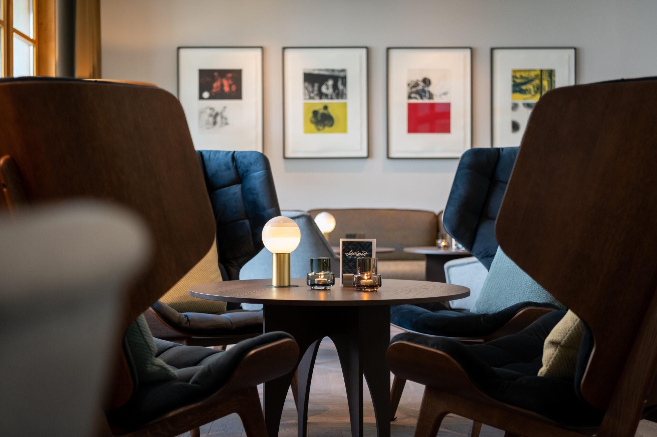 Elegante Hotellounge mit modernen Sesseln, stimmungsvoller Tischbeleuchtung und gerahmten Kunstwerken für eine gemütliche Atmosphäre.