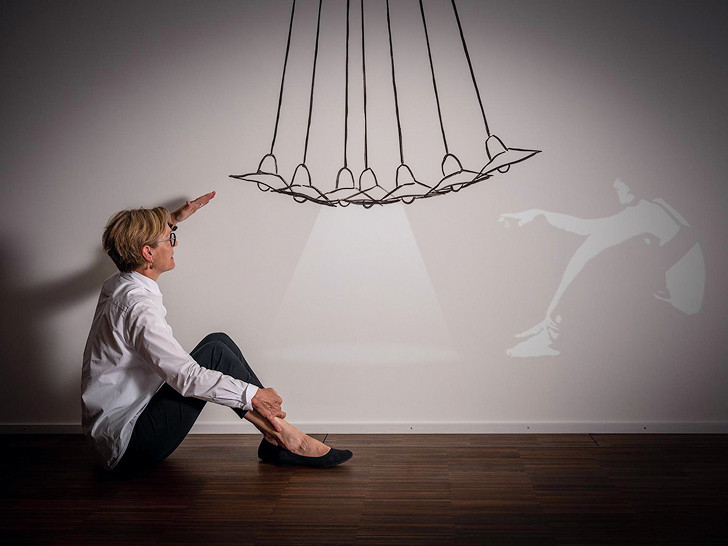 Frau Züllig sitzt auf dem Boden und schaut sich eine Kunstinstallation an im Hotel Schweizerhof.