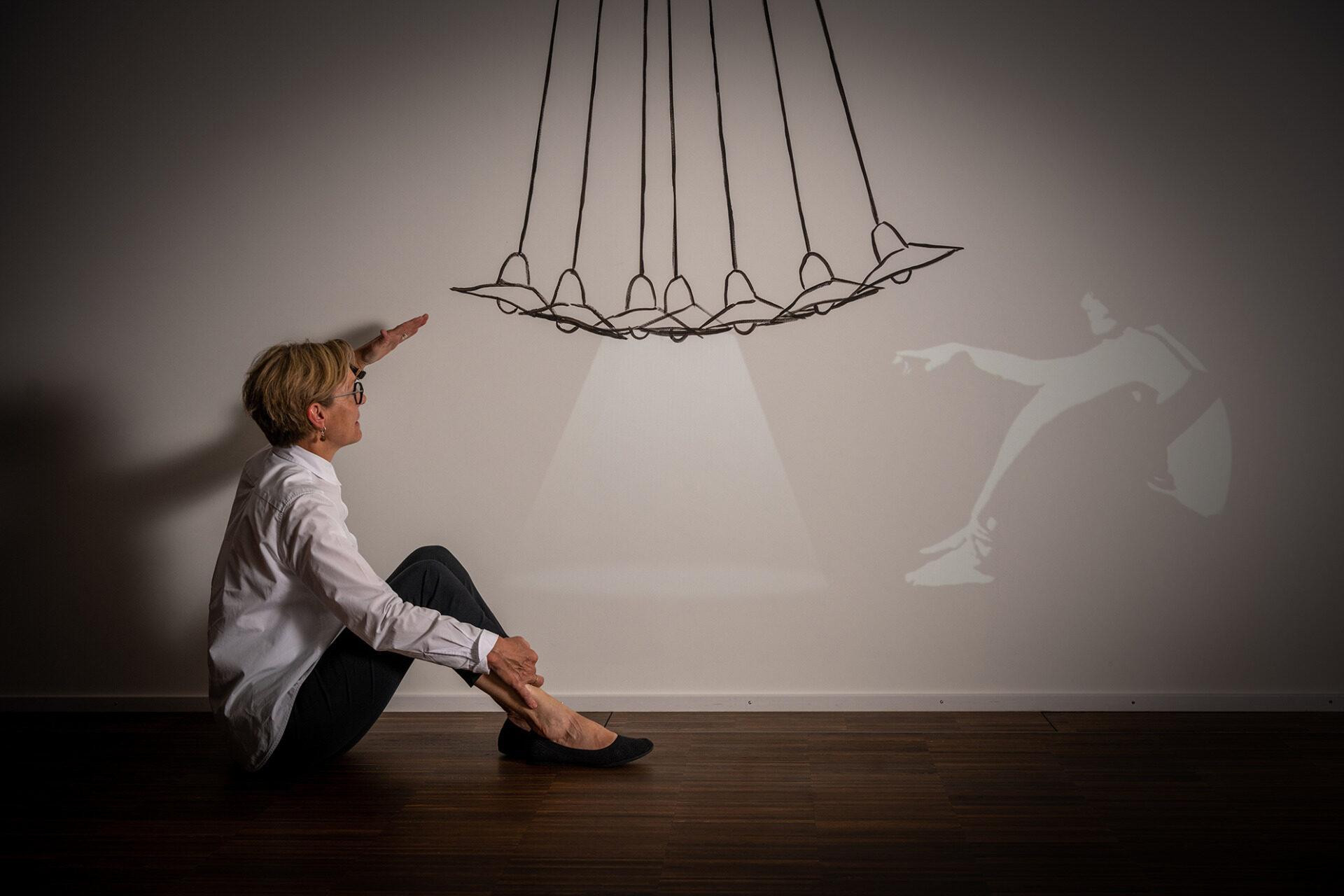 Frau Züllig sitzt auf dem Boden und schaut sich eine Kunstinstallation an im Hotel Schweizerhof.