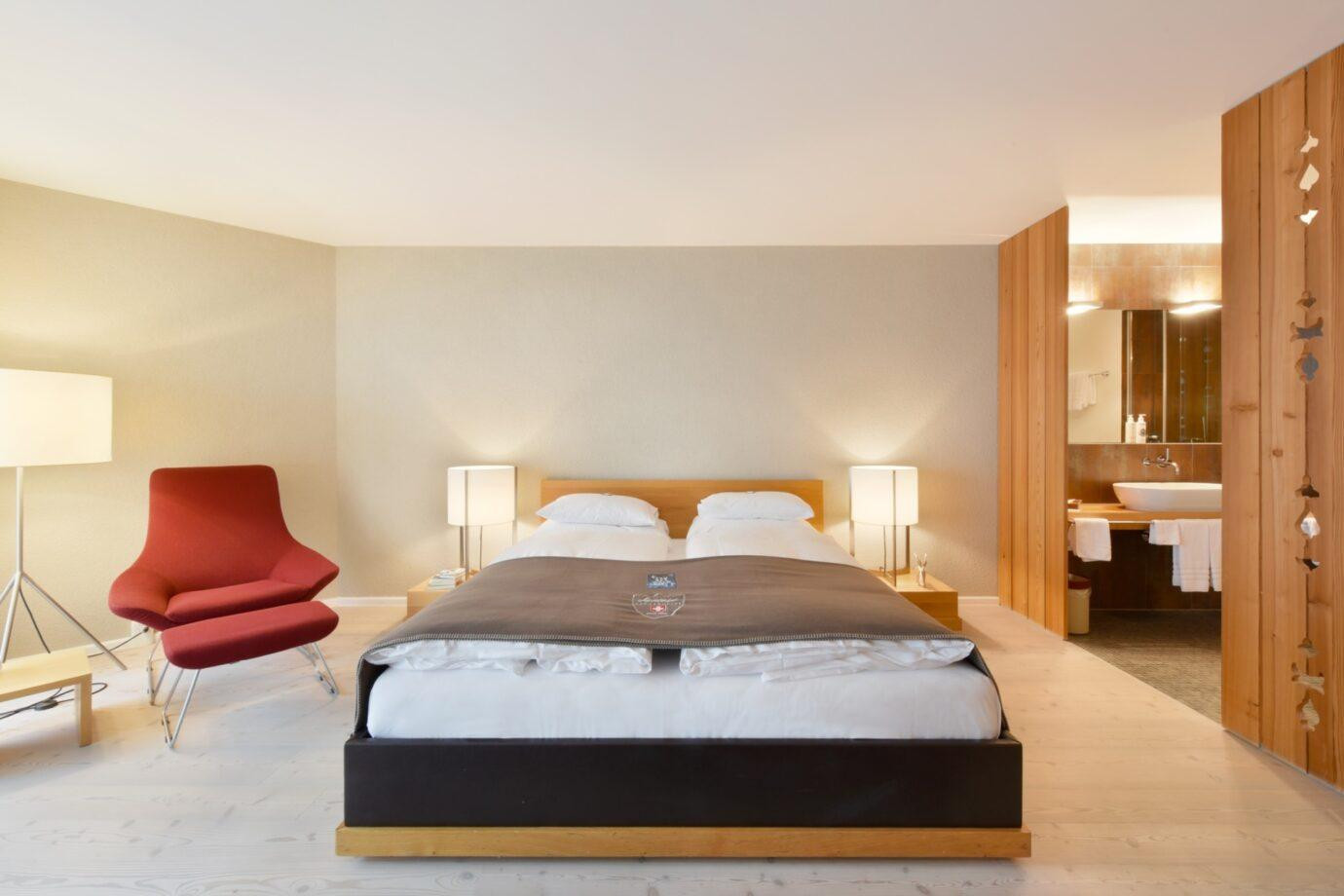 Grosszügiges und gemütliches Kingsize-Bett mit einem Sessel und Holztrennelement