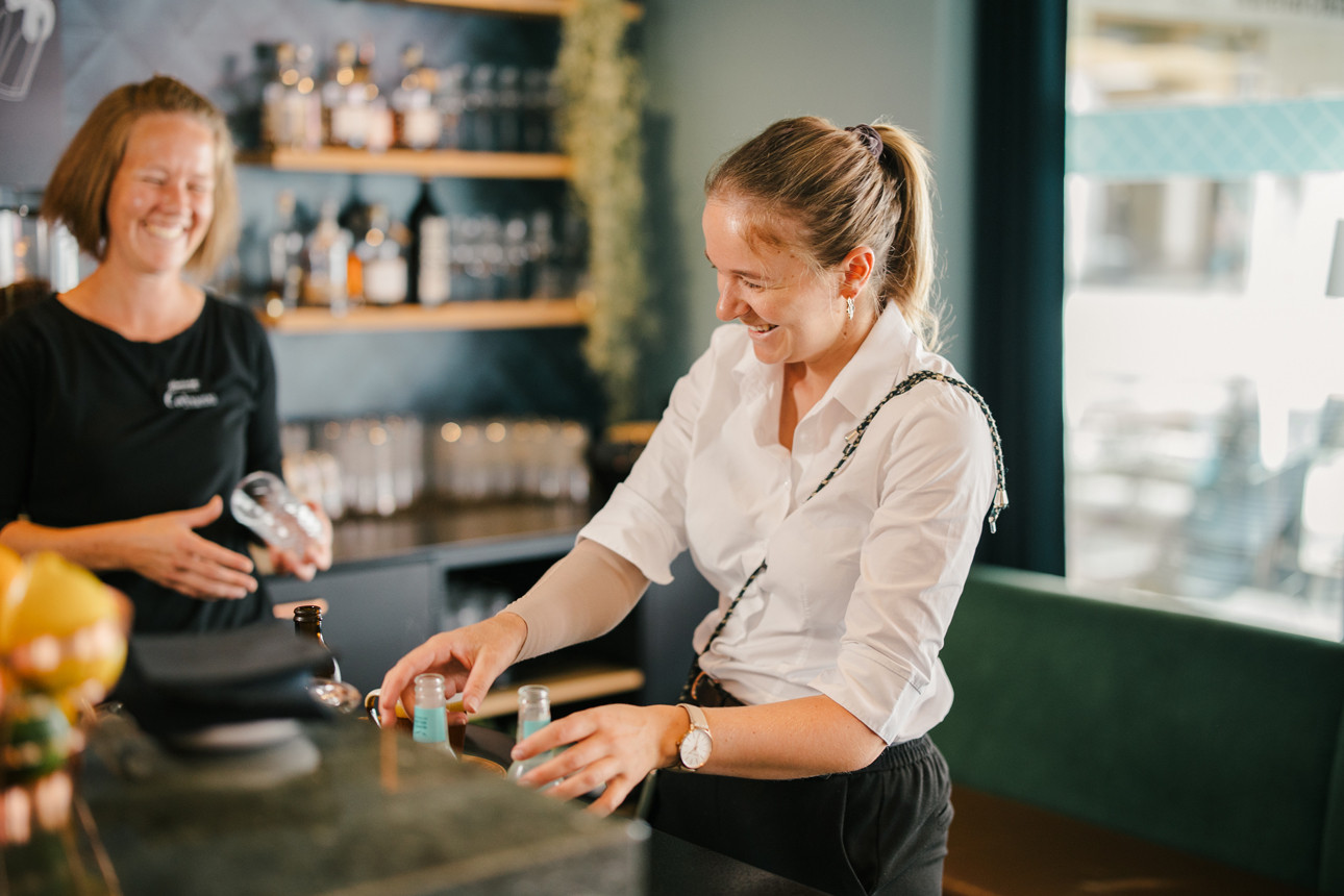 Mitarbeiterin im Service welche mit einer anderen Mitarbeiterin spricht und lacht.