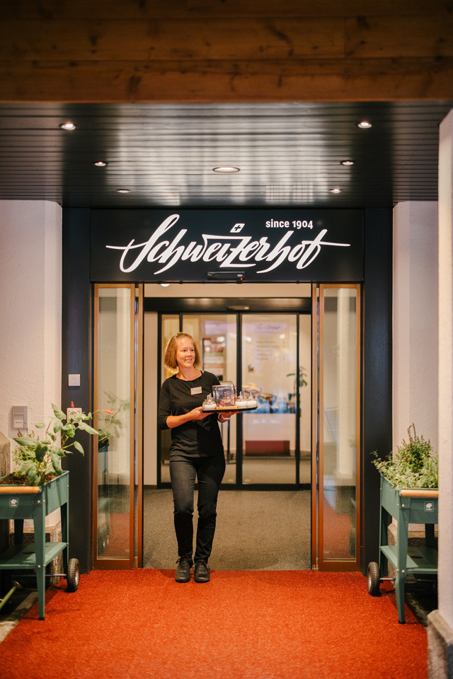 Mitarbeiterin vom Service im Eingang des Hotels mit einem Tablar mit Essen