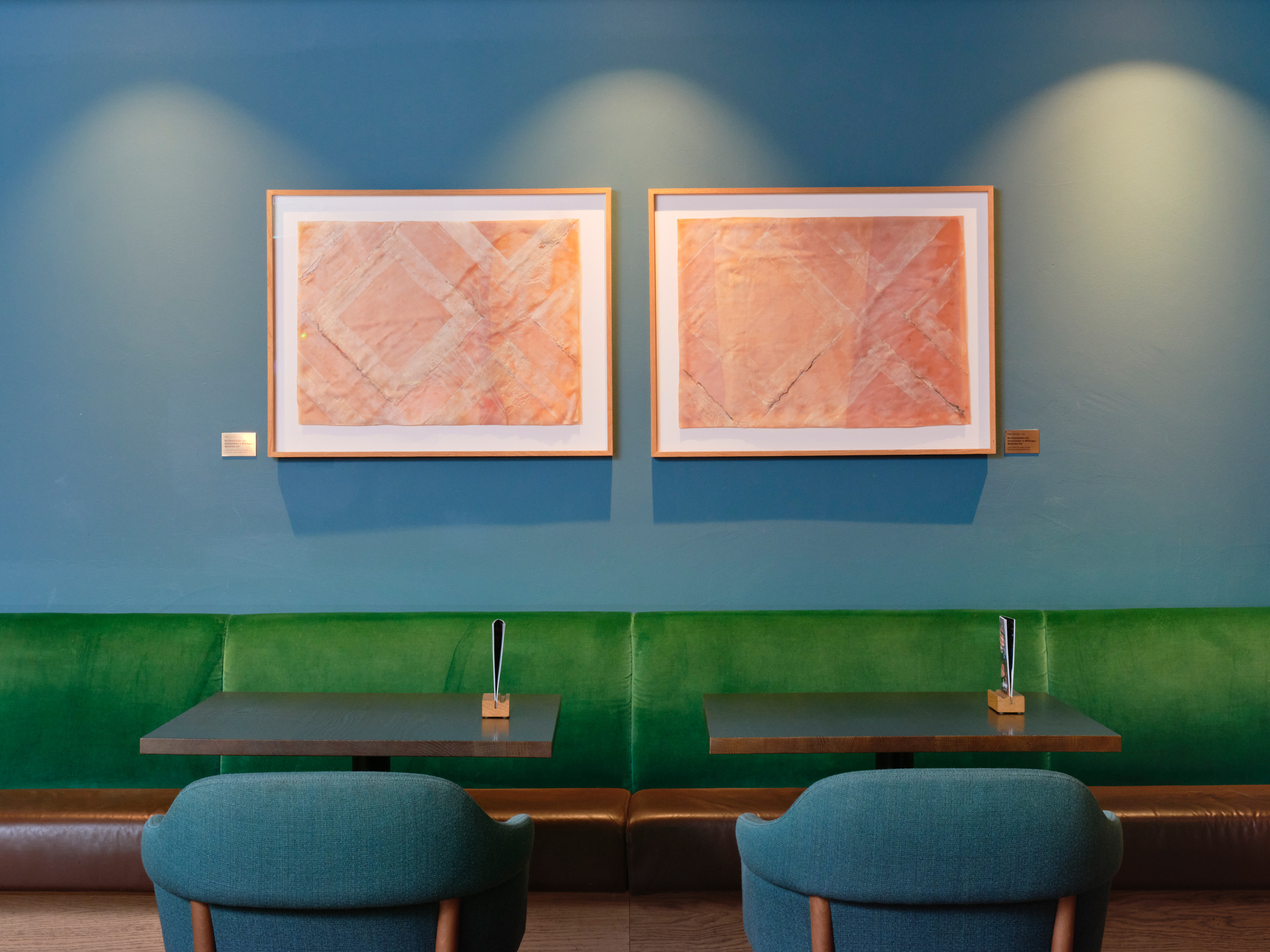 Zwei lachsfarbene Kunstwerke auf petrolfarbener Wand