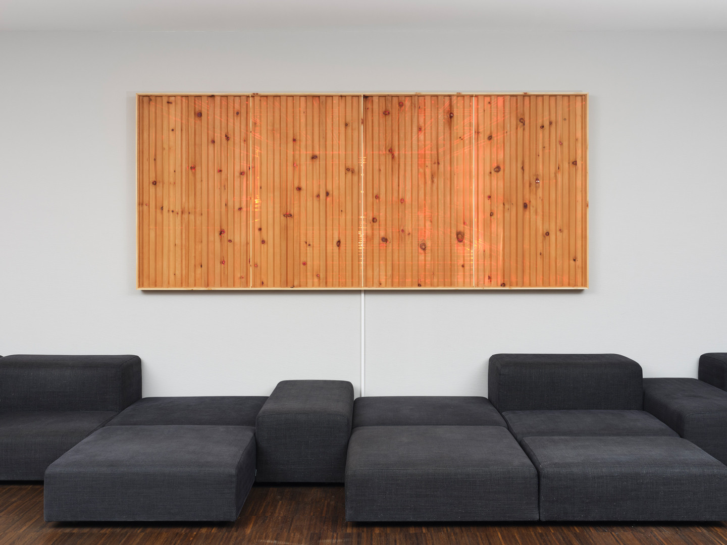 Ein Kunstwerk das oberhalb eines Sofas an der Wand hängt