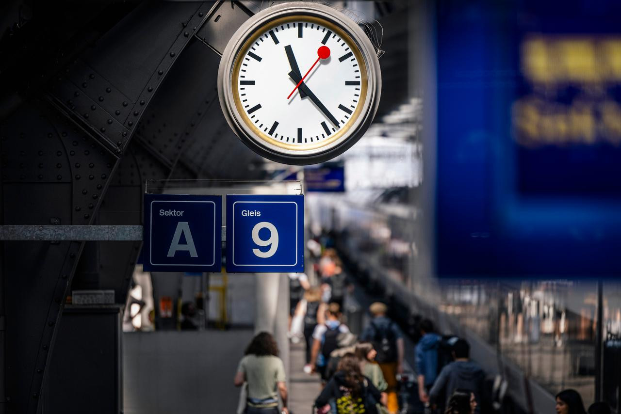 Eine SBB Stations-Uhr und unter der Uhr viele Menschen die in eine Richtung laufen