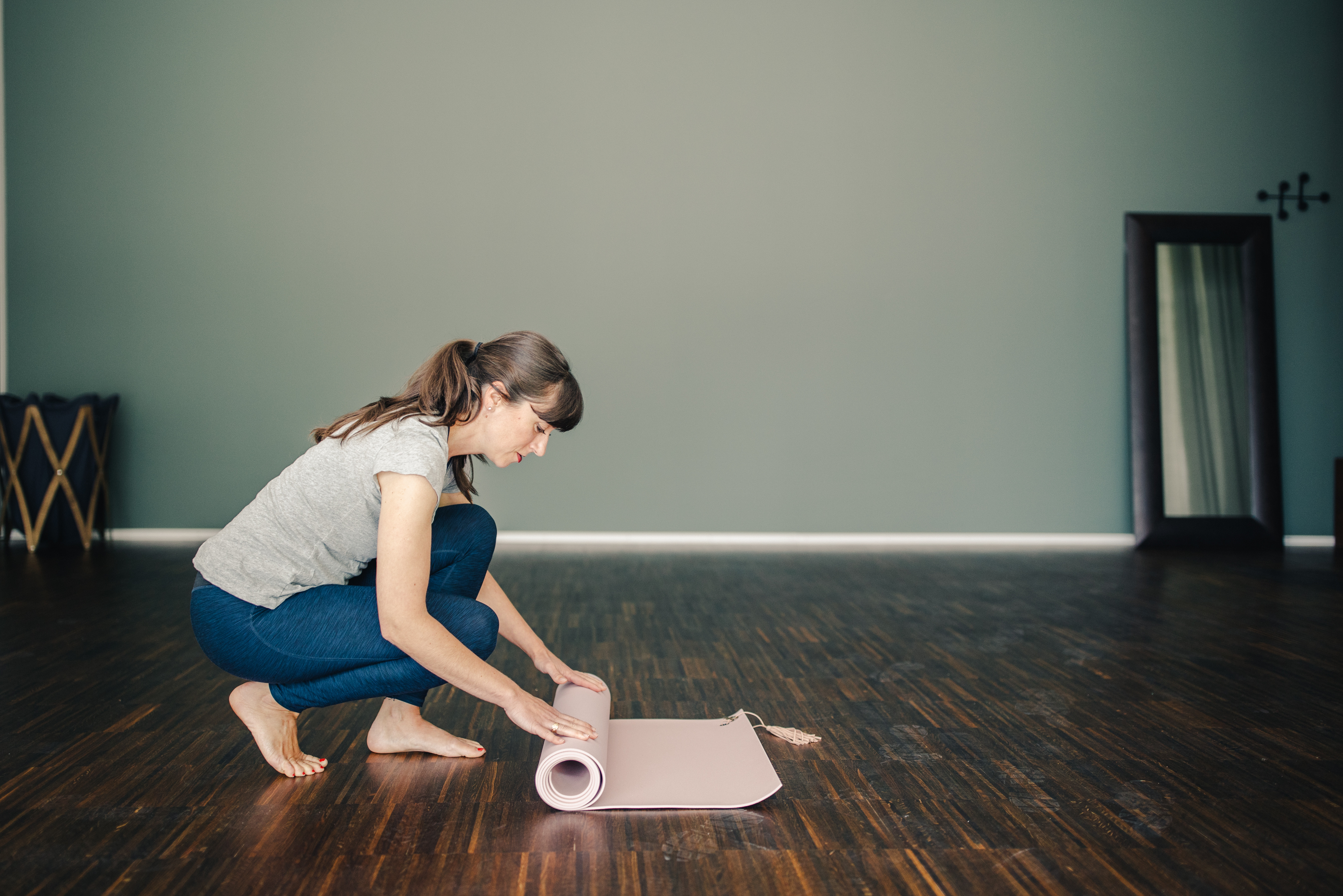 Eine Dame, die im Bewegungs- und Entspannungsraum eine Yogamatte zusammenrollt.