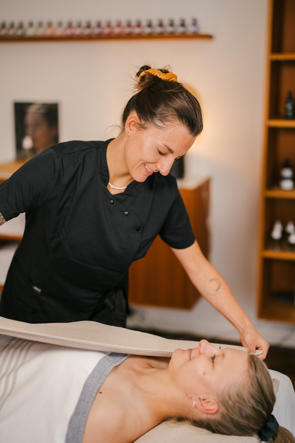 Eine Masseurin deckt die behandelnde Gästin zu.
