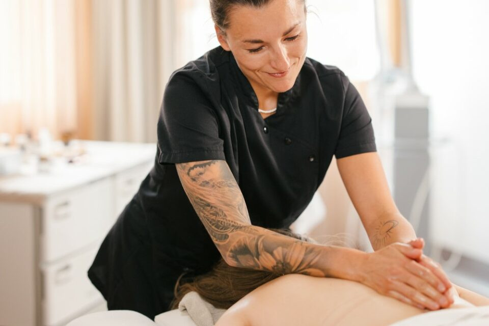 Eine Masseurin massiert den Rücken der Patientin
