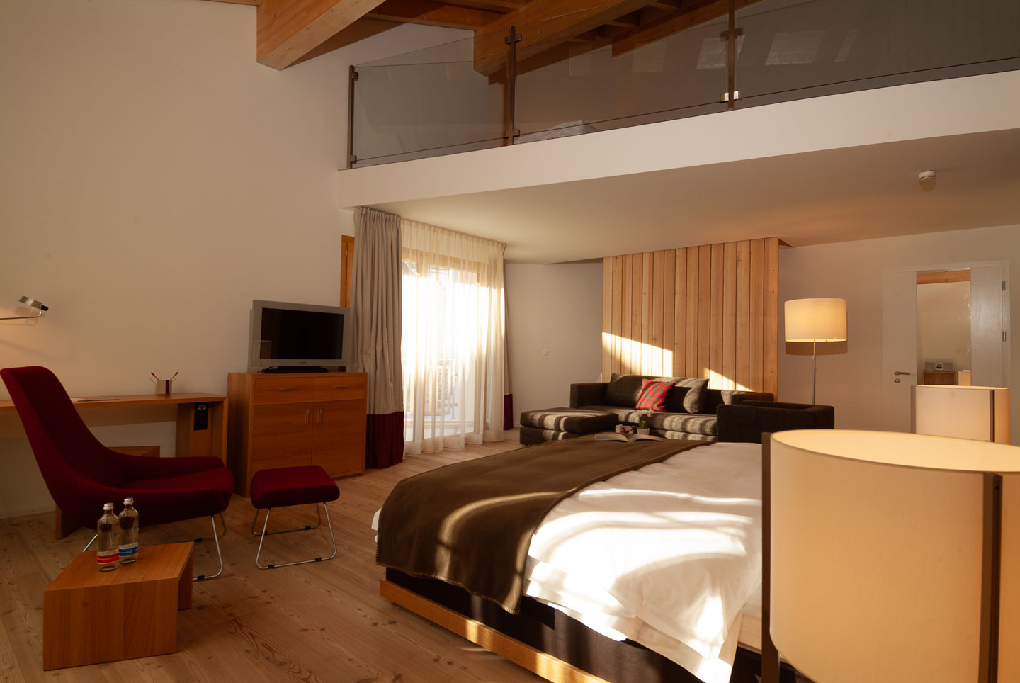 Alpenchic Suite mit Gallerie mit offenem Schlafbereich, gemütlicher Sitzecke und warmen Holzelementen.