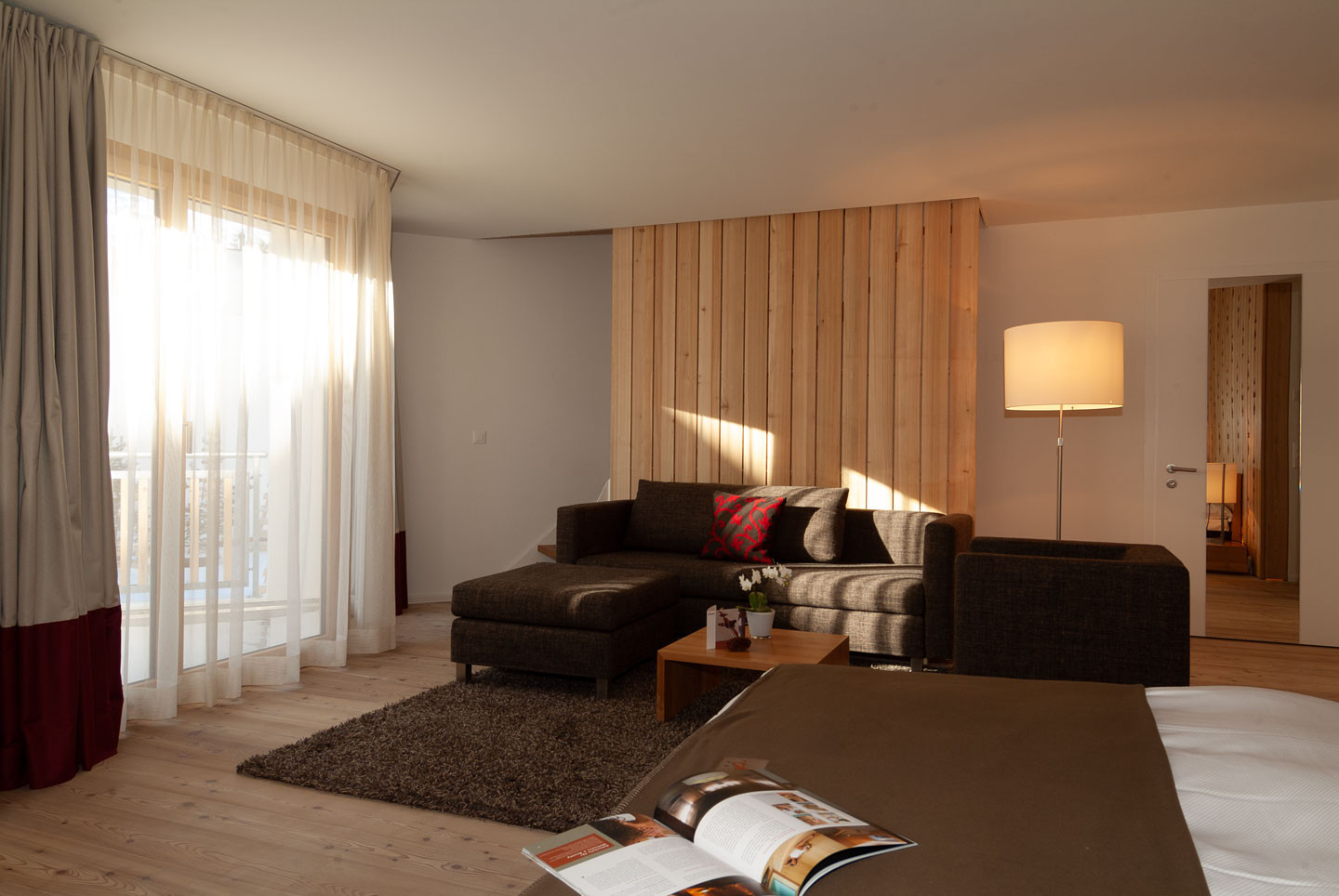 Alpenchic Suite mit gemütlicher Loungeecke, warmem Lichteinfall und natürlichen Holzelementen.