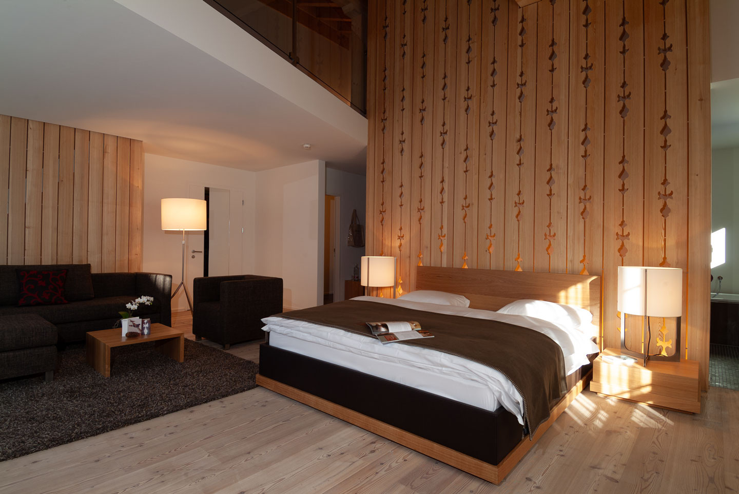 Alpenchic Suite mit Galerie mit stilvollem Doppelbett, gemütlicher Sitzecke und kunstvoller Holzvertäfelung.