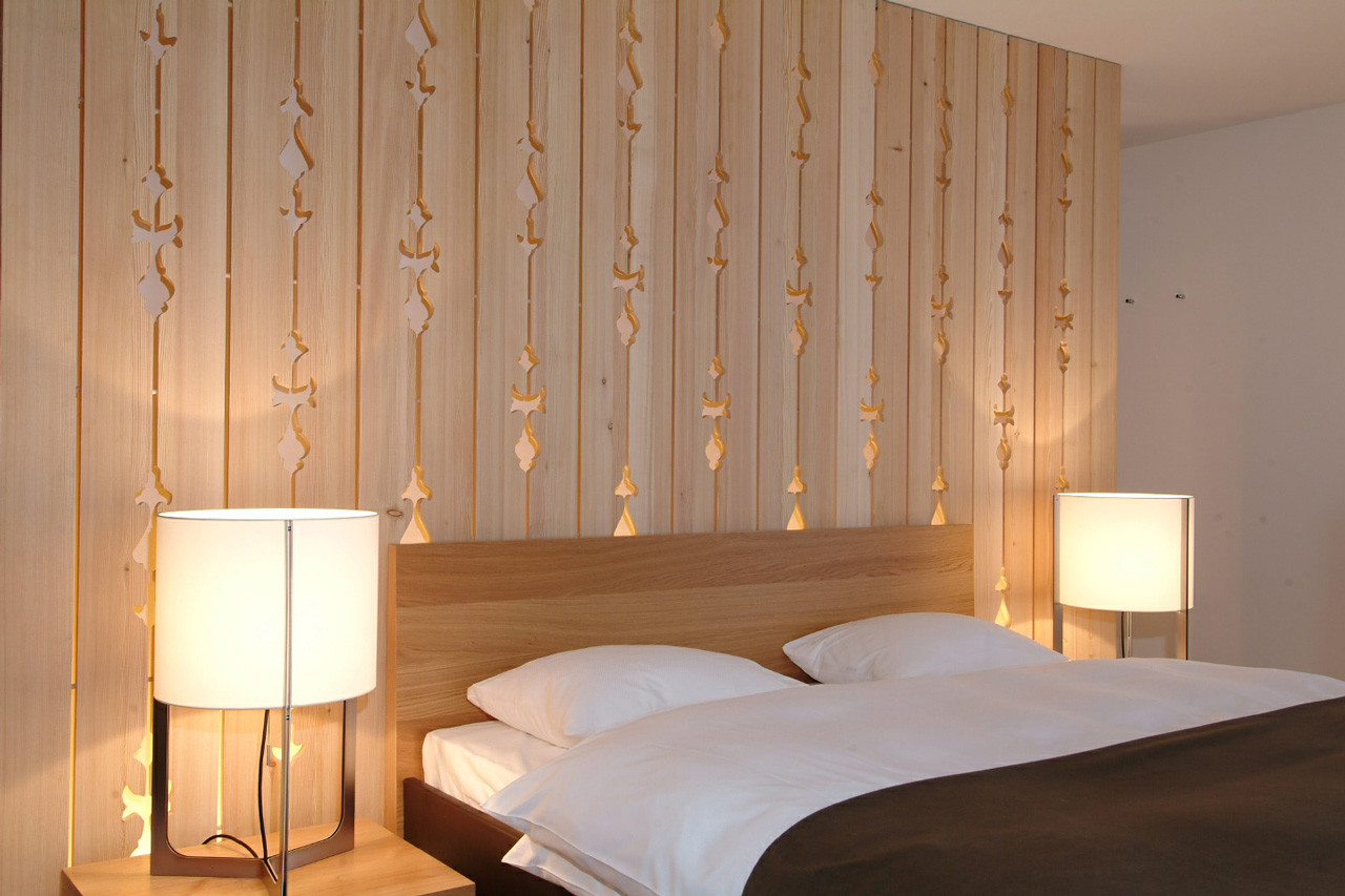 Nahaufnahme des Doppelbettes mit Holzwand und Nachttischlampen mit Lampen.