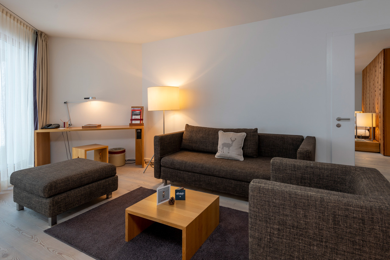 Sofaecke mit Beistelltisch auf einem Teppich und Schreibtisch mit einem Hocker.