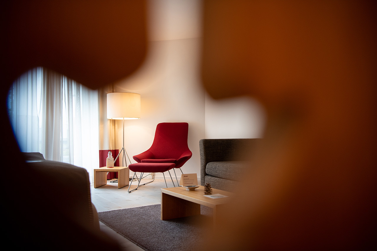 Helles Alpenchic Zimmer mit modernem Lounge-Sessel und holzige Innenausstattung.