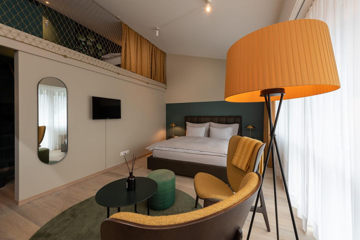 ChatGPT: Nostalchic Belle Étage Zimmer mit gemütlicher Sitzgruppe, elegantem Doppelbett und offenem Galeriegeschoss.