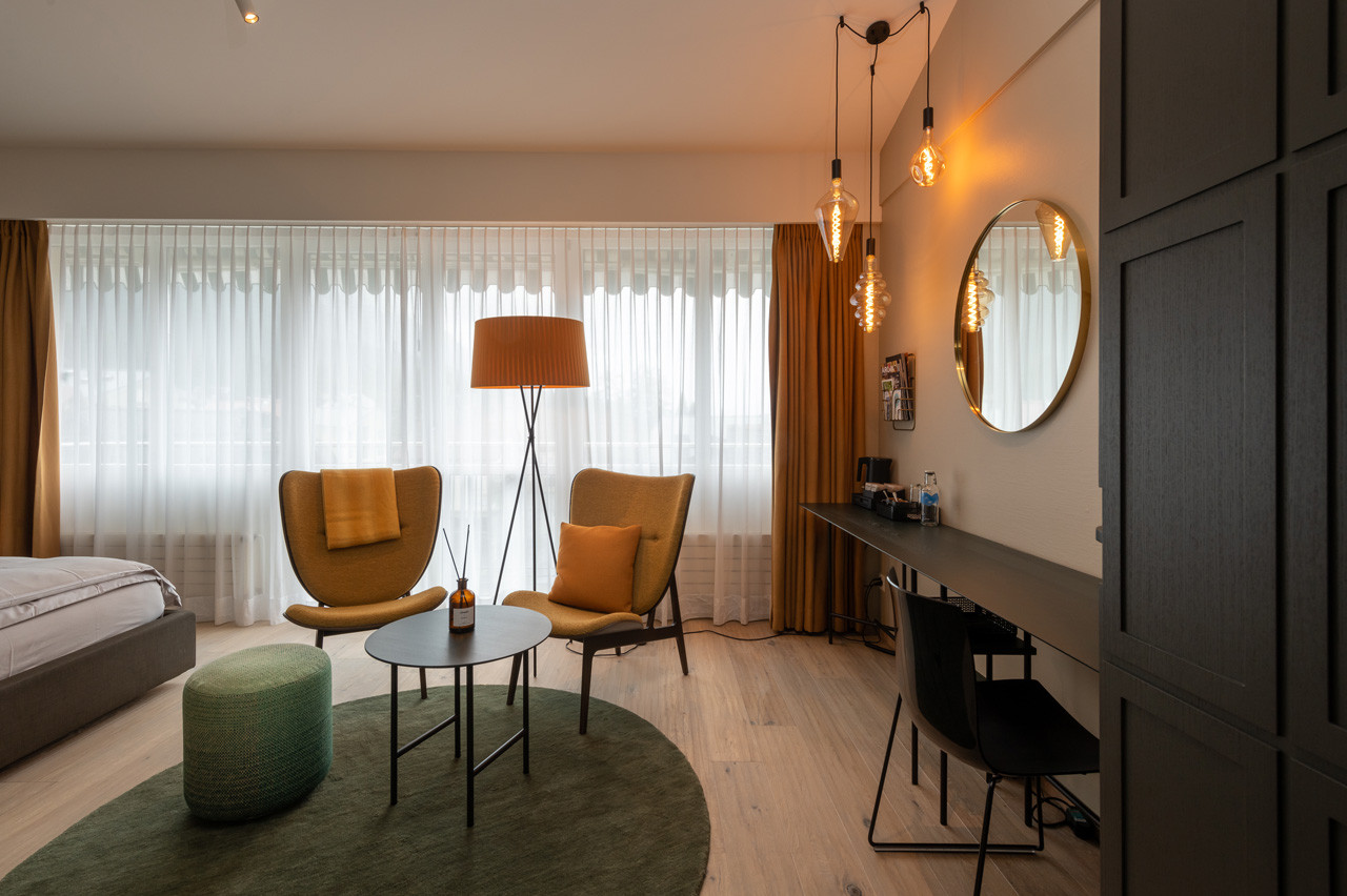 Nostalchic Belle Étage Zimmer mit stilvoller Sitzgruppe, warmem Licht und modernem Schreibtischbereich.