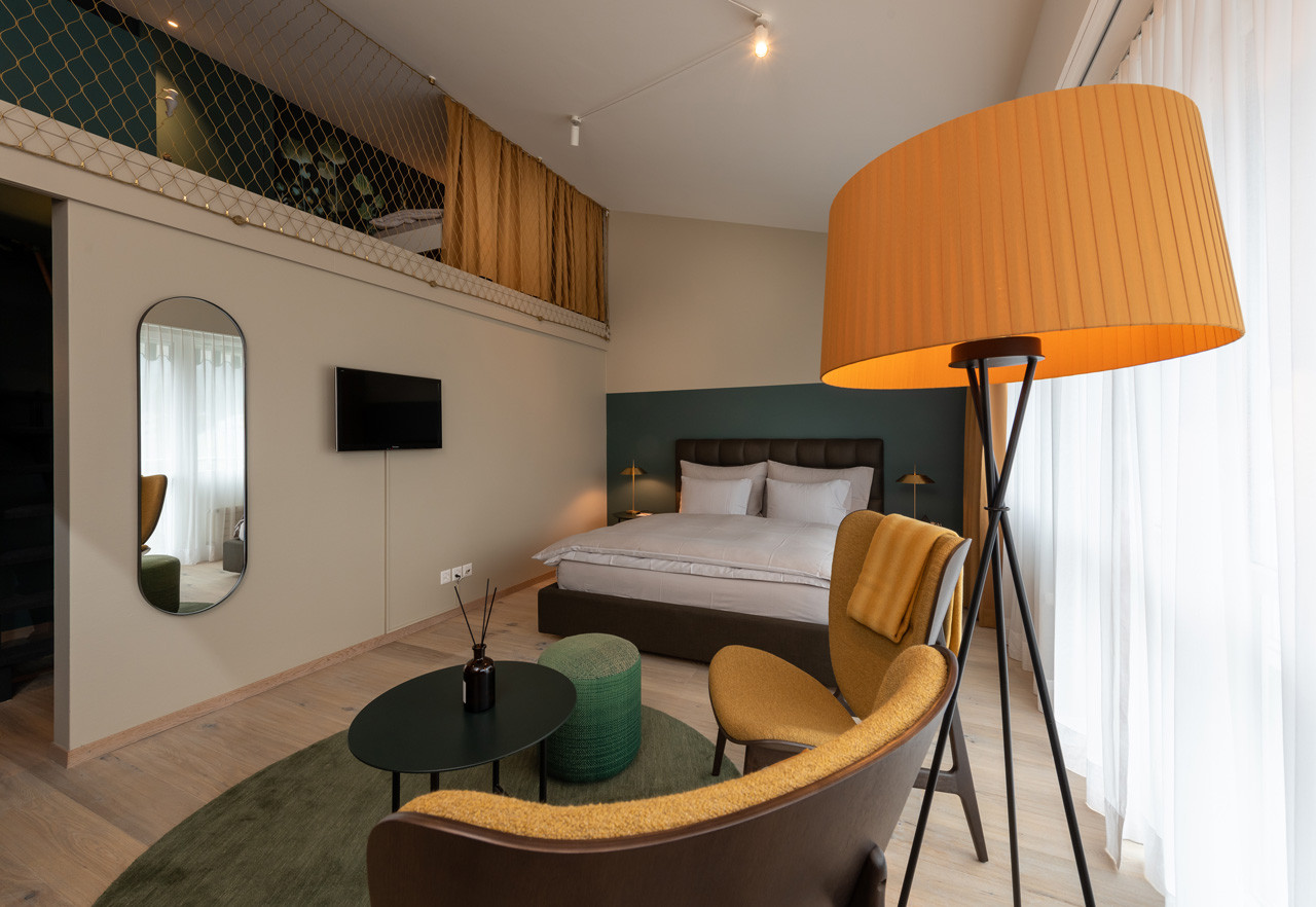 Nostalchic Belle Étage Zimmer mit gemütlicher Sitzgruppe, elegantem Doppelbett und offenem Galeriegeschoss.