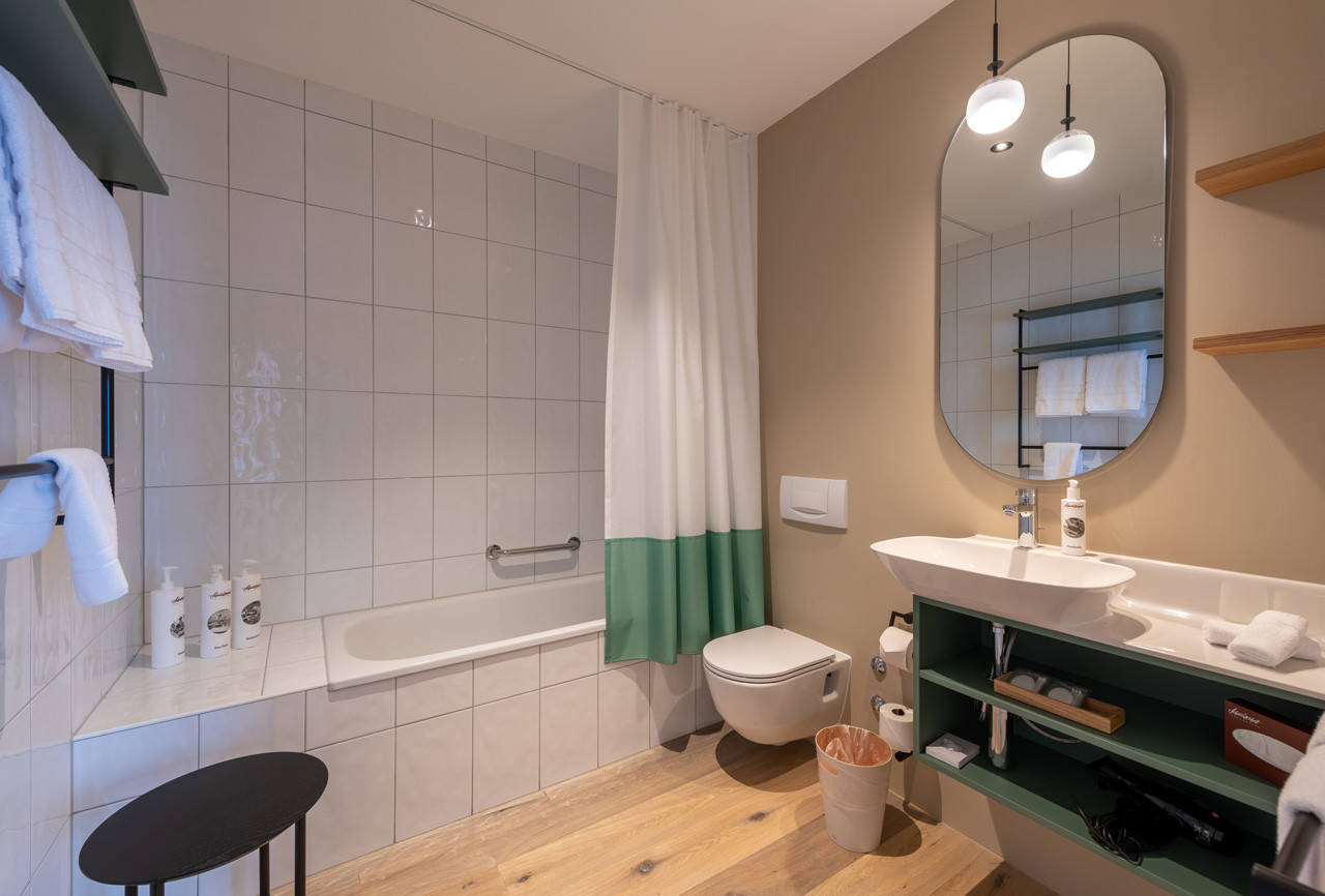 Helles Badezimmer im Nostalchic Stil mit Badewanne, grossem Spiegel und modernen Akzenten.