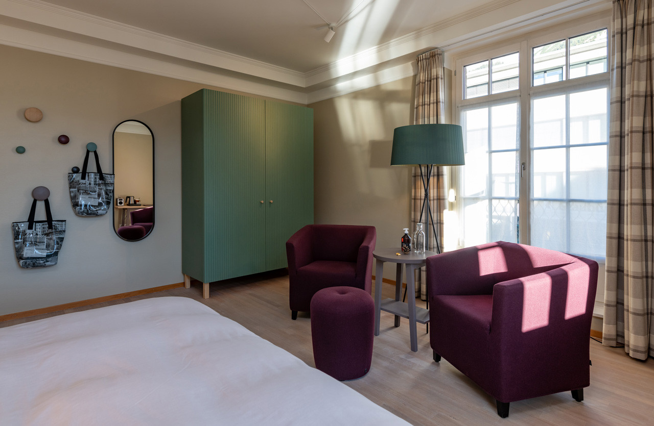 Nostalchic Zimmer mit farblich abgestimmter Sitzgruppe, grossem Kleiderschrank und hellem Tageslicht.