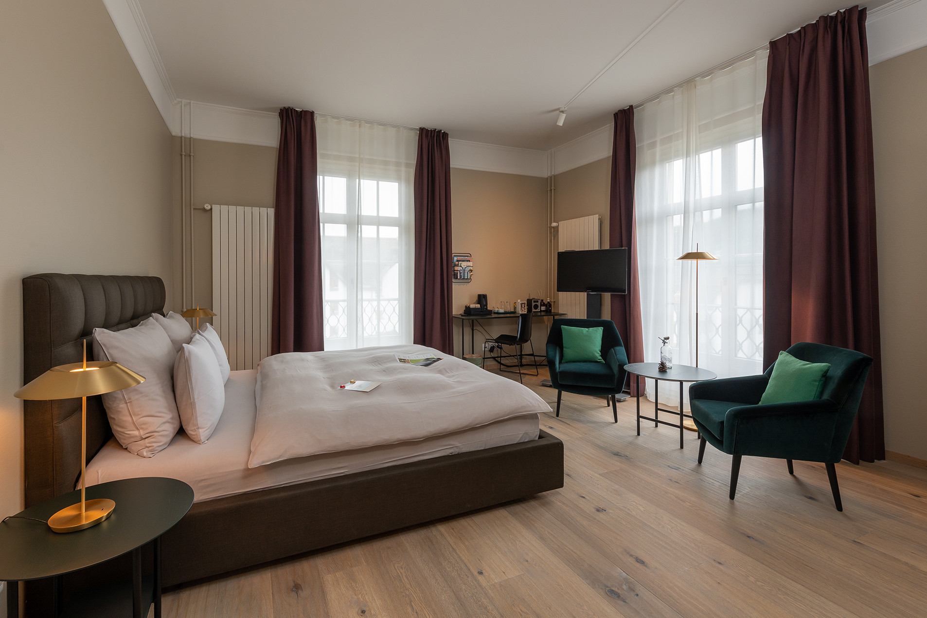 Nostalchic Zimmer mit elegantem Doppelbett, warmen Naturtönen und gemütlicher Sitzgruppe am Fenster.
